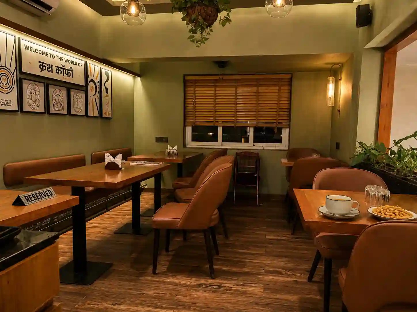 Earthy sage green walls and cozy wooden tables inside Crush Coffee CG Road Ahmedabad