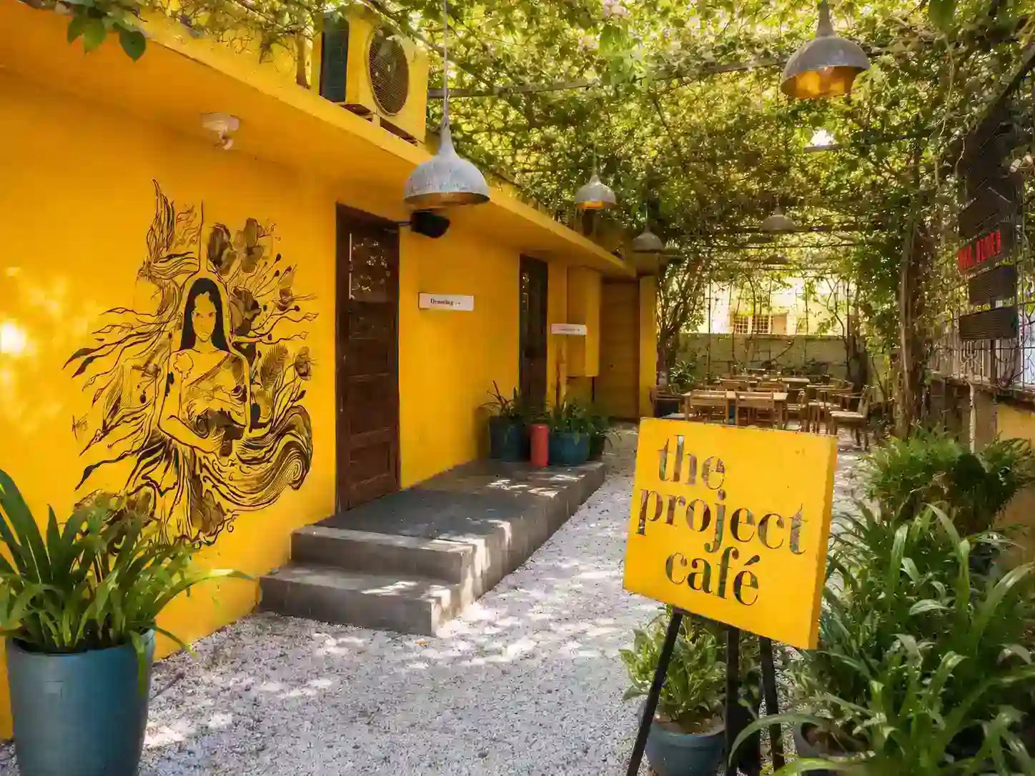 Vibrant yellow wall and courtyard dining area at The Project Cafe Navrangpura Ahmedabad
